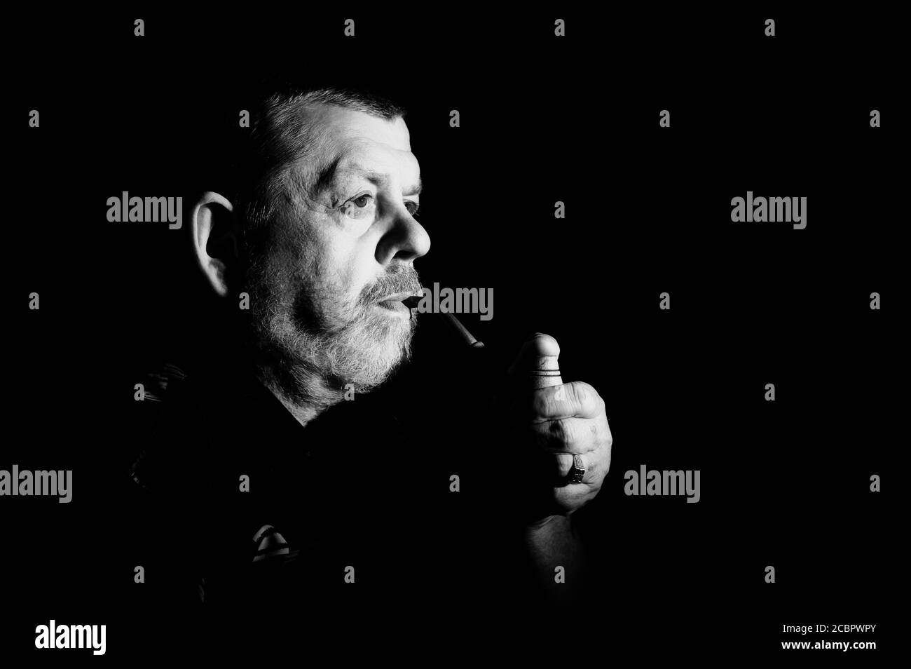 Bel ritratto nero e bianco drammatico di caucasico senior fumo tubo di tabacco nell'oscurità Foto Stock