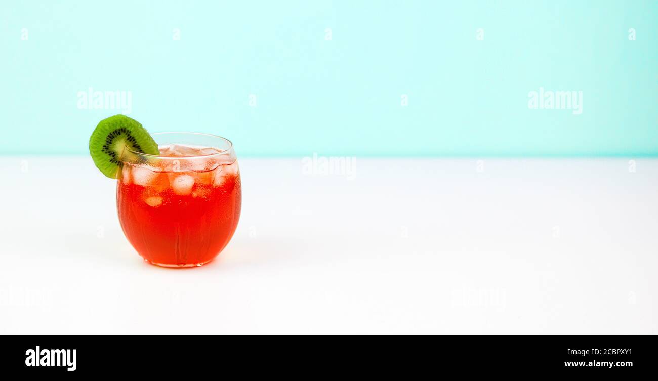 cocktail rosso con fetta di kiwi su sfondo blu chiaro e bianco Foto Stock