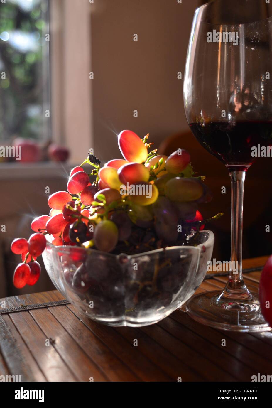 Un vaso con uva da tavola rosa e un classico bicchiere di vino rosso Foto Stock