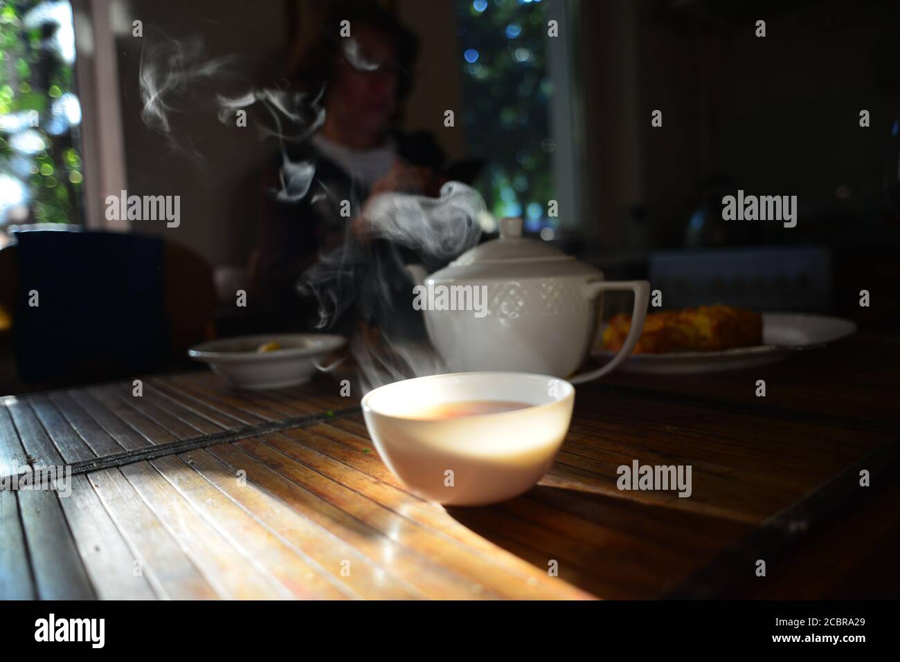 Un servizio di tè nero, con una tazza di porcellana fumante di tè e bestiame da tè. Foto Stock