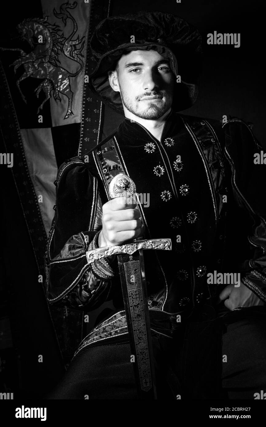 Ritratto di re attraente con barba vestita in costume spada e guardando la fotocamera Foto Stock