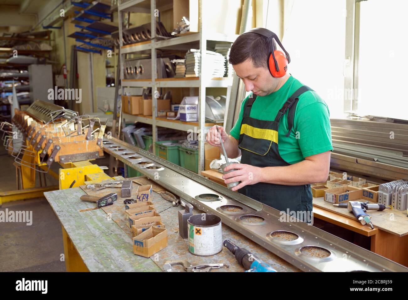 Operatore che applica un rivestimento resistente alla corrosione su una parte della fusoliera di piano leggero presso il negozio di assemblaggio Foto Stock