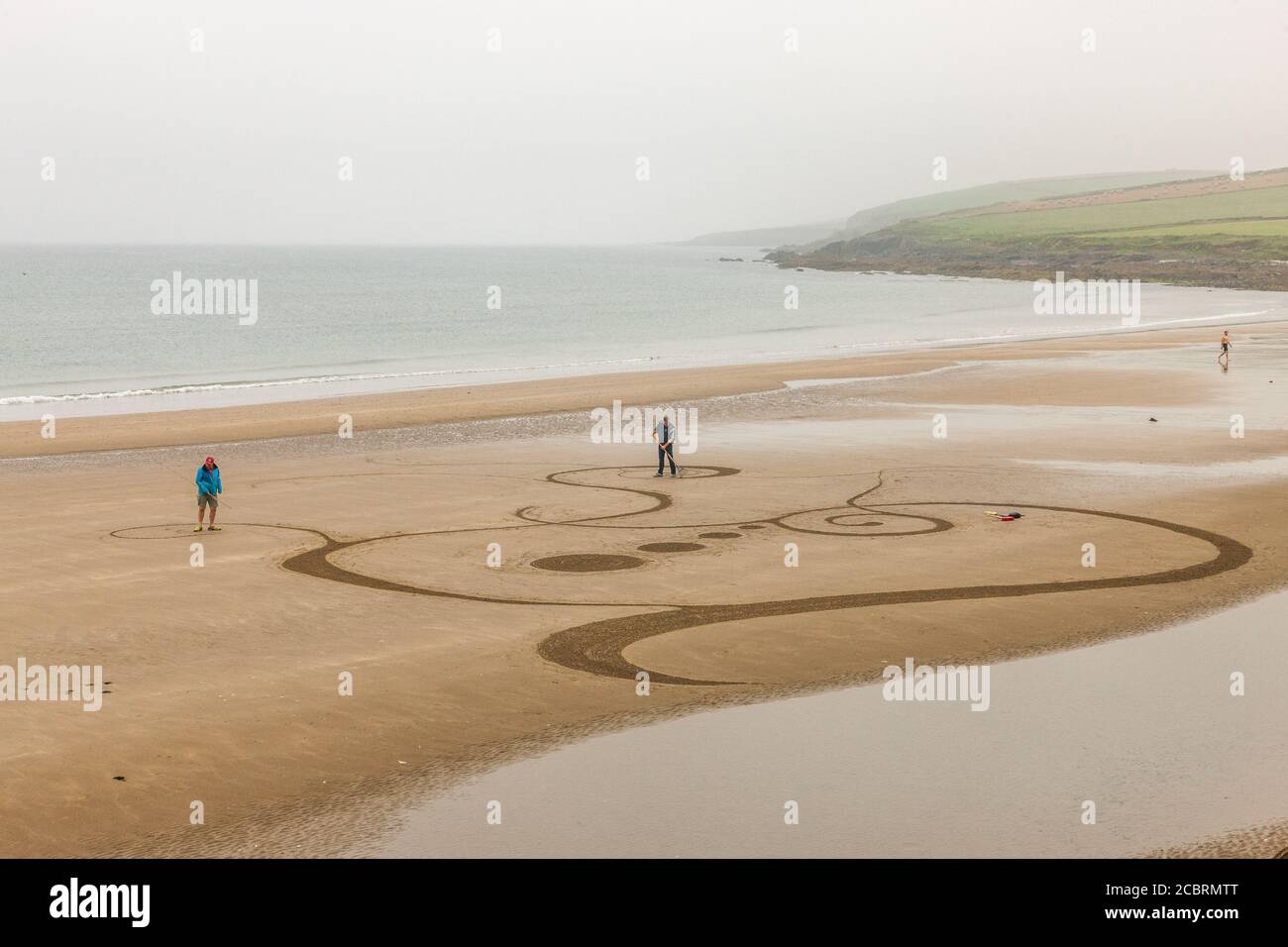 Garrettstown, Cork, Irlanda. 15 agosto. Christin Jambou e Tom Clancy di Kinsale creano disegni di sabbia di Celtic Art mentre la marea è fuori sulla spiaggia a Garrettstown, Co. Cork, Irlanda. - credito; David Creedon / Alamy Live News Foto Stock