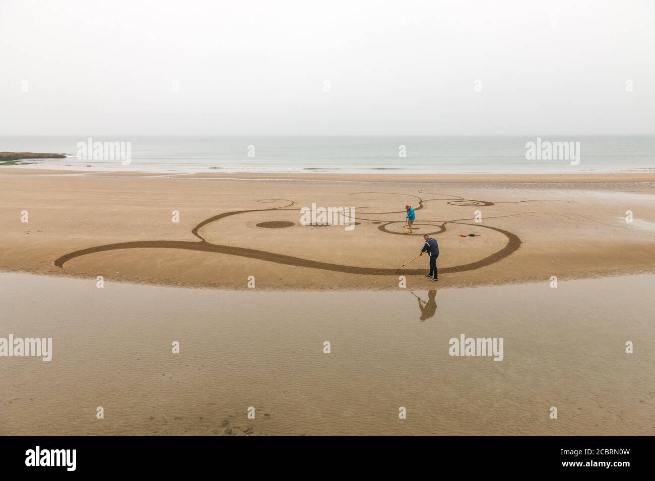 Garrettstown, Cork, Irlanda. 15 agosto. Christin Jambou e Tom Clancy di Kinsale creano disegni di sabbia di Celtic Art mentre la marea è fuori sulla spiaggia a Garrettstown, Co. Cork, Irlanda. - credito; David Creedon / Alamy Live News Foto Stock