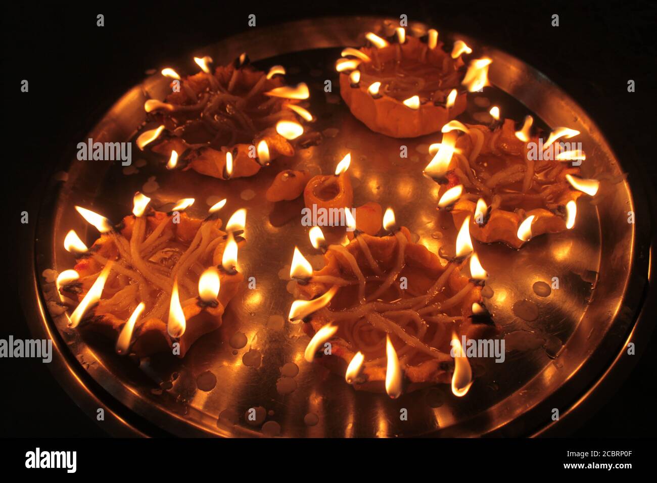 una piastra di rame con 60 lampade in indiano impasto di pane messo sul fuoco Foto Stock