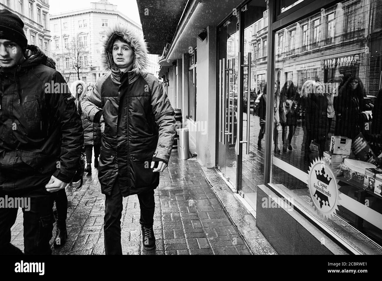 Guardare nella fotocamera. Ragazzi fuori in una giornata invernale piovosa. Lviv/Ucraina - 30 gennaio 2020: La gente cammina lungo la via Akademika Hnatyuka Foto Stock