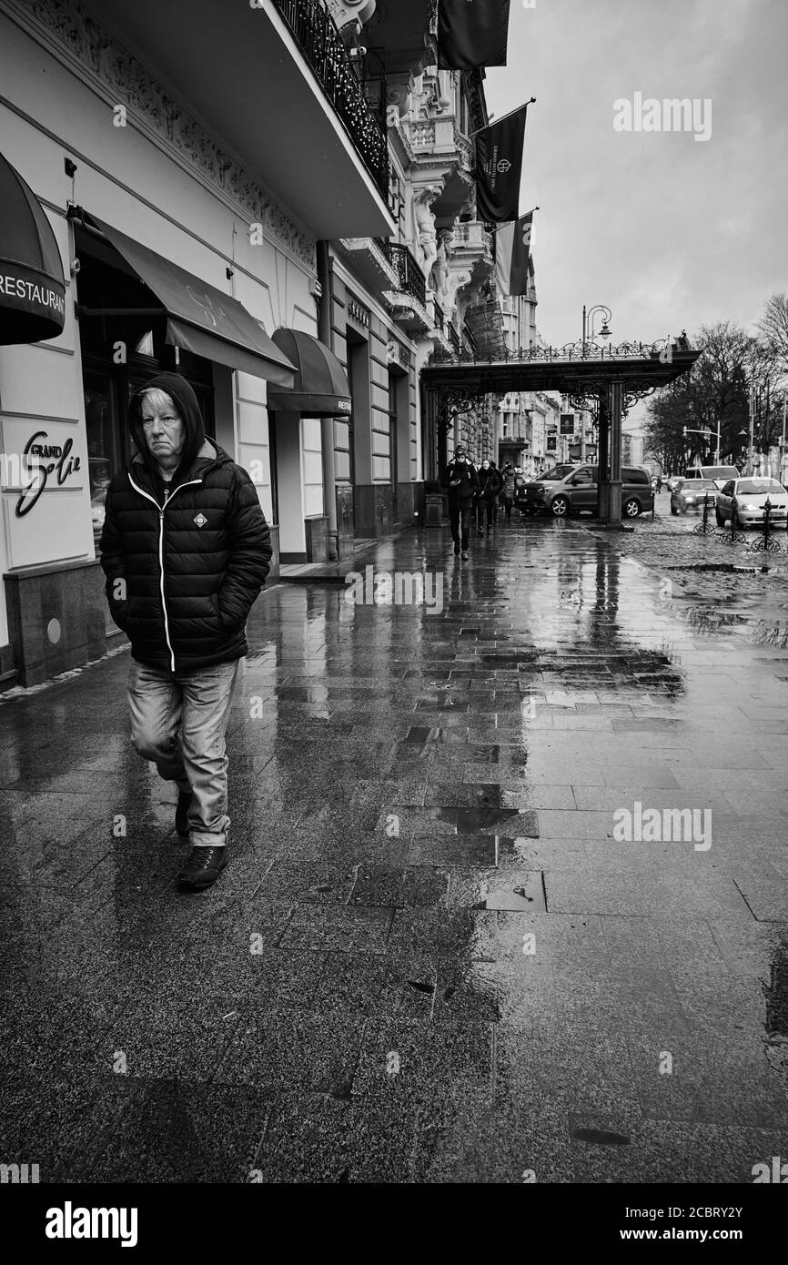 Uomo pioggia. Lviv/Ucraina - 30 gennaio 2020: Un uomo coraggioso di cattivo umore cammina lungo il viale (Prospect Svobody). Foto Stock