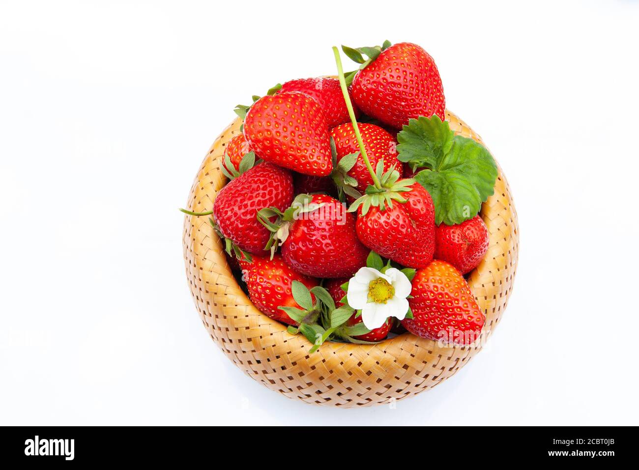 maturare bella fragola in un cesto di vimini con fiore visualizza Foto Stock