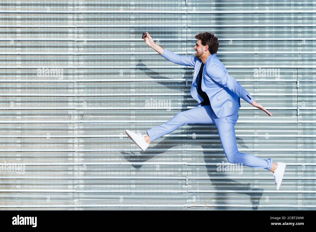 L'uomo che indossa un costume fa un selfie con uno smartphone durante il salto Foto Stock