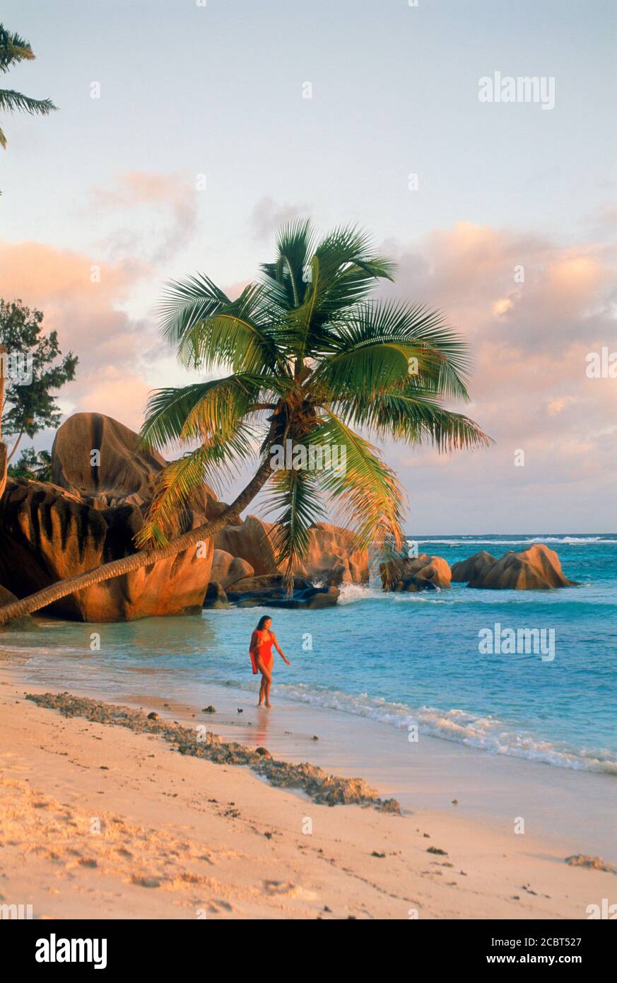 La donna da sola il La Digue Island in Seychelles nella luce del tramonto con rocce granitiche e riva sabbiosa Foto Stock