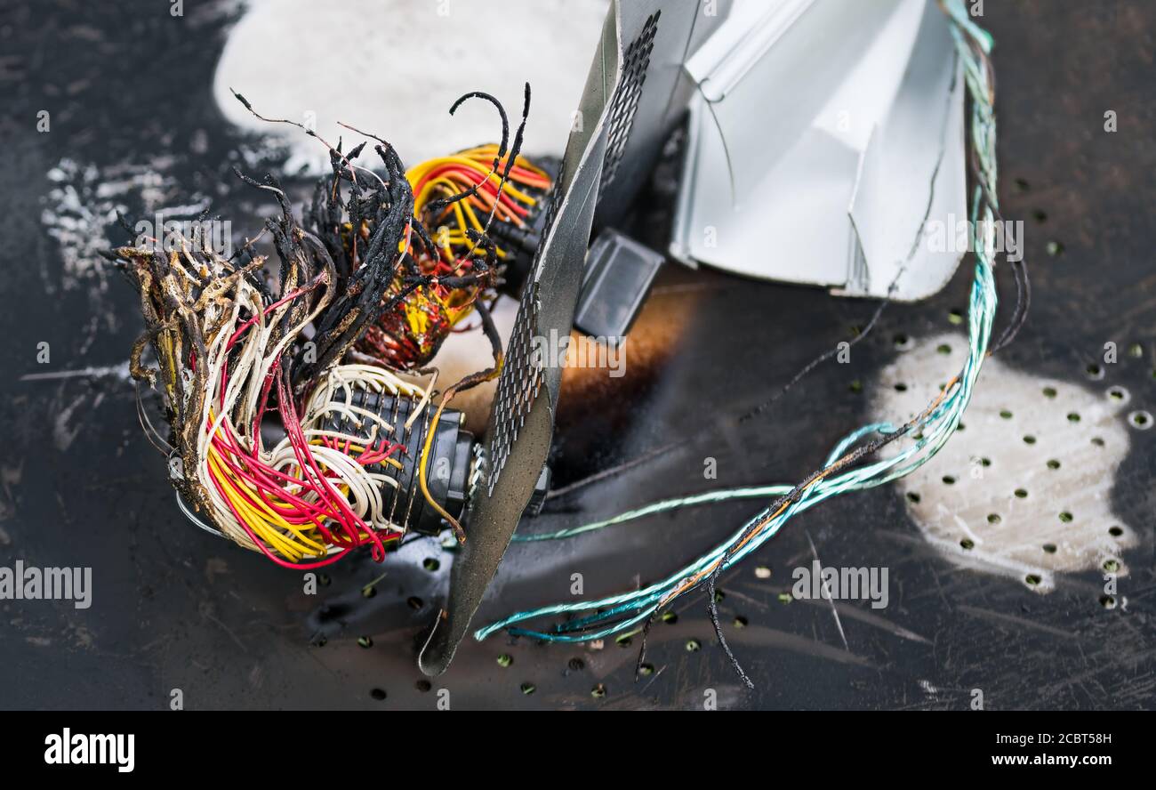 Closeup di relitti bruciati da traffico o incidente industriale. Cavi elettrici colorati danneggiati dal fuoco. Interruttore coperchio plancia. Incidente aereo, auto o treno. Foto Stock