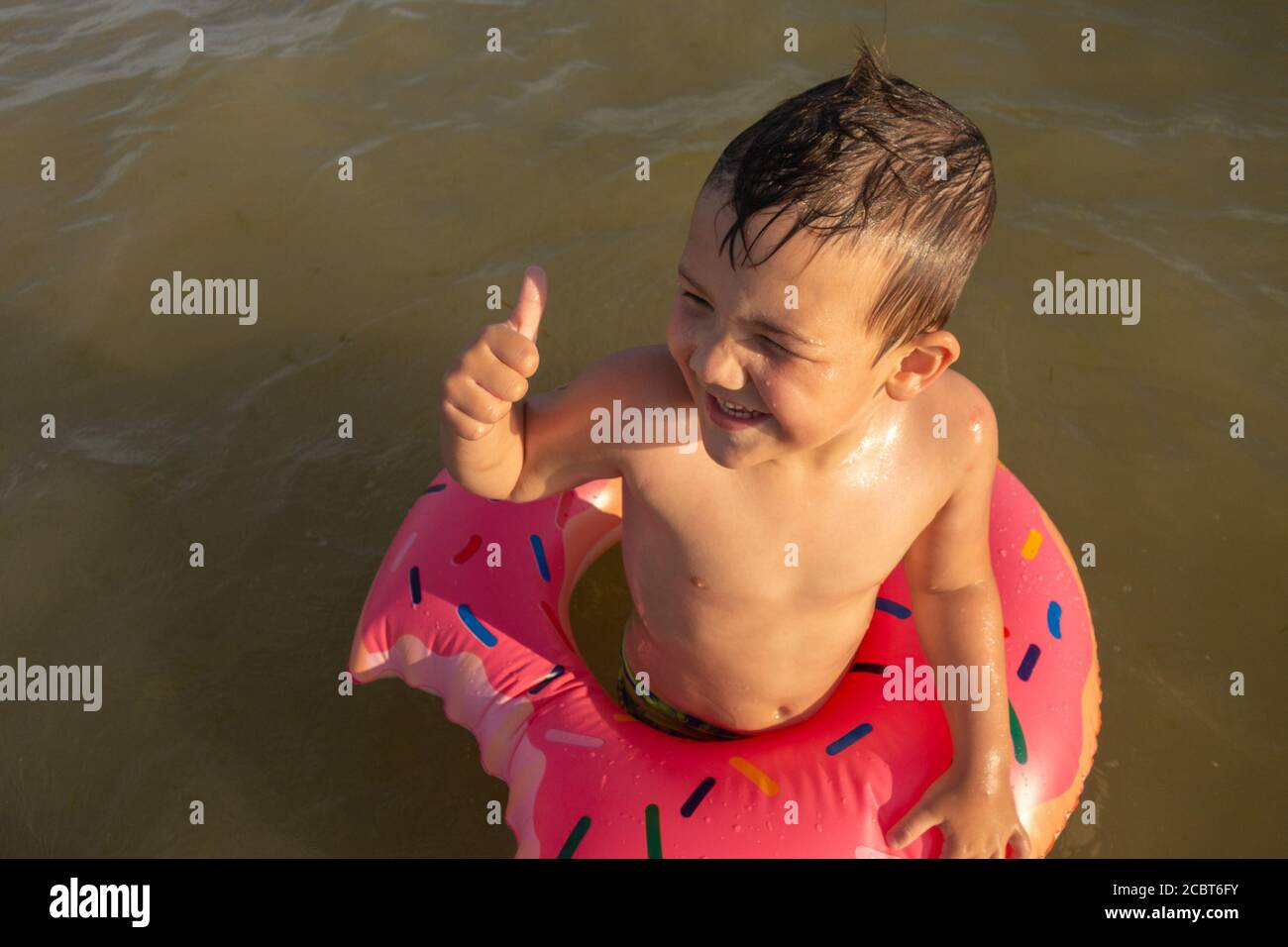 un ragazzo di 5 anni che nuota in mare in una bagnoschiera mostra un simile. Foto Stock