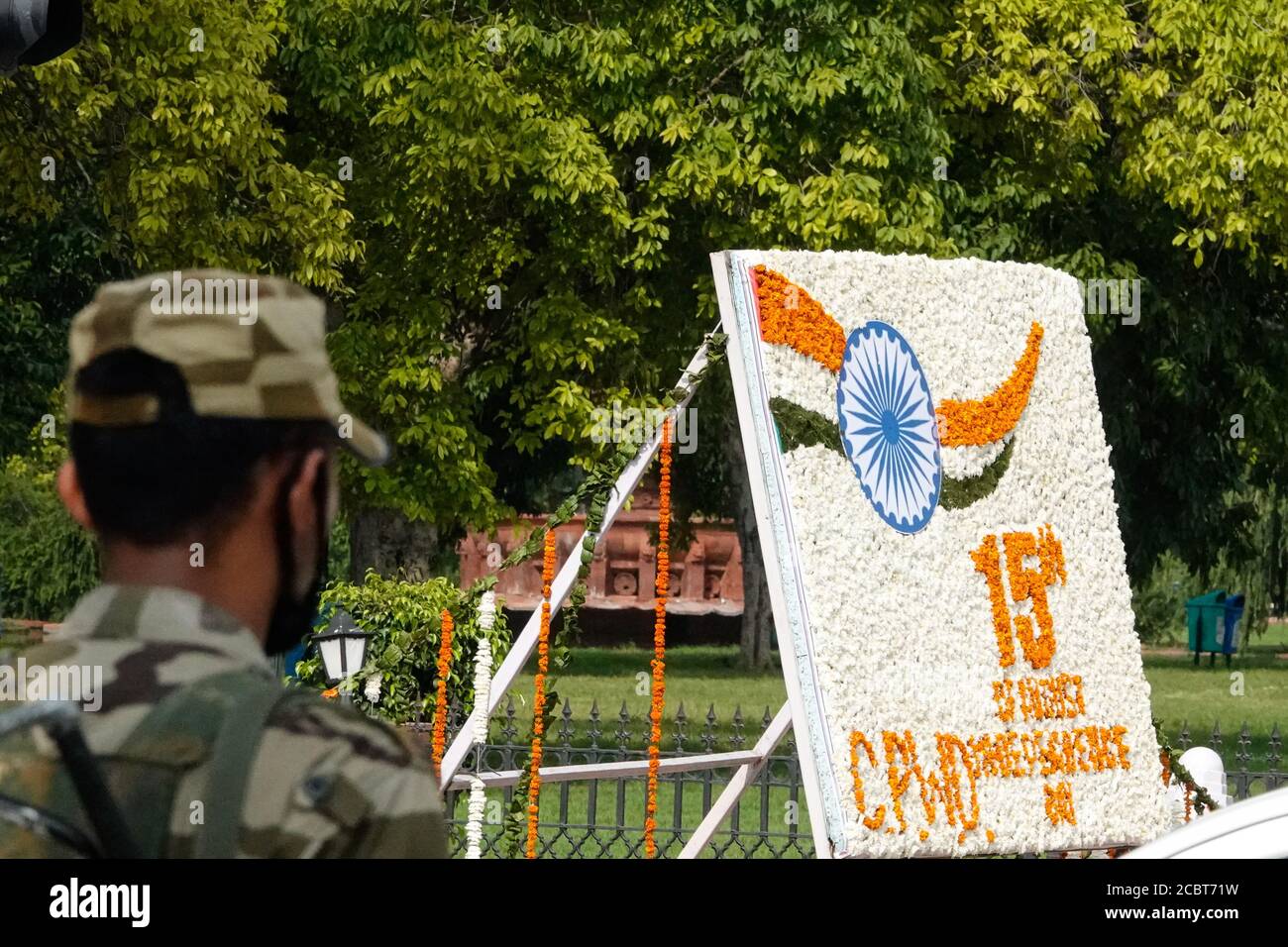 Decorazione floreale con scritto 15 agosto CPWD persone di India Festeggiando la giornata dell'indipendenza indiana nella capitale nazionale Delhi e nell'esercito persona che indossa una maschera in camouflage con pistola per sicurezza Per felice 74esima giornata di Indipendenza su strade e strade decorate Con bandiere nazionali tricolore e in mezzo a Covid-19 coronavirus pandemia focolaio nel 2020 Foto Stock