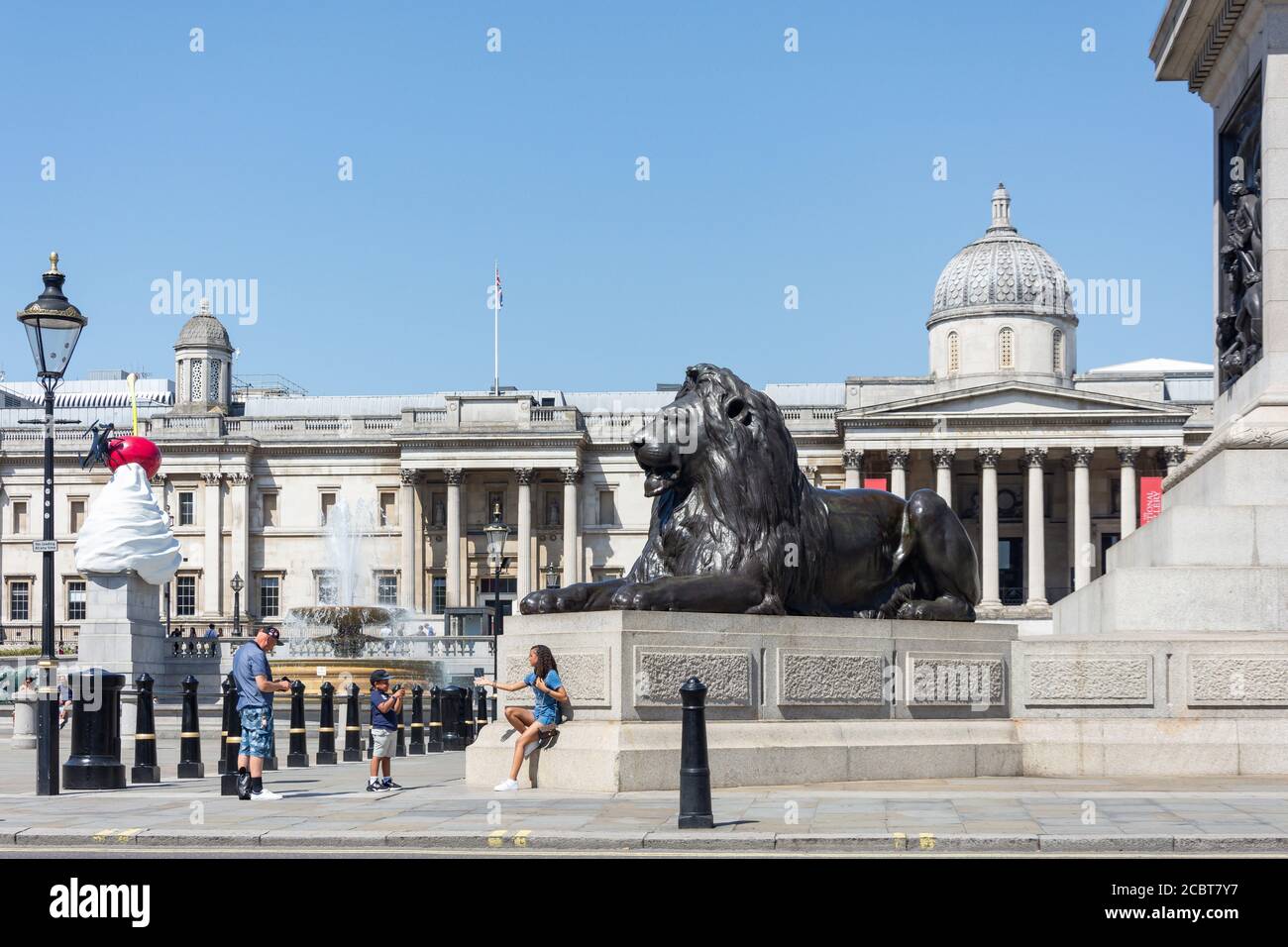 Statue leoni alla base della colonna di Nelson, Trafalgar Square, City of Westminster, Greater London, England, Regno Unito Foto Stock