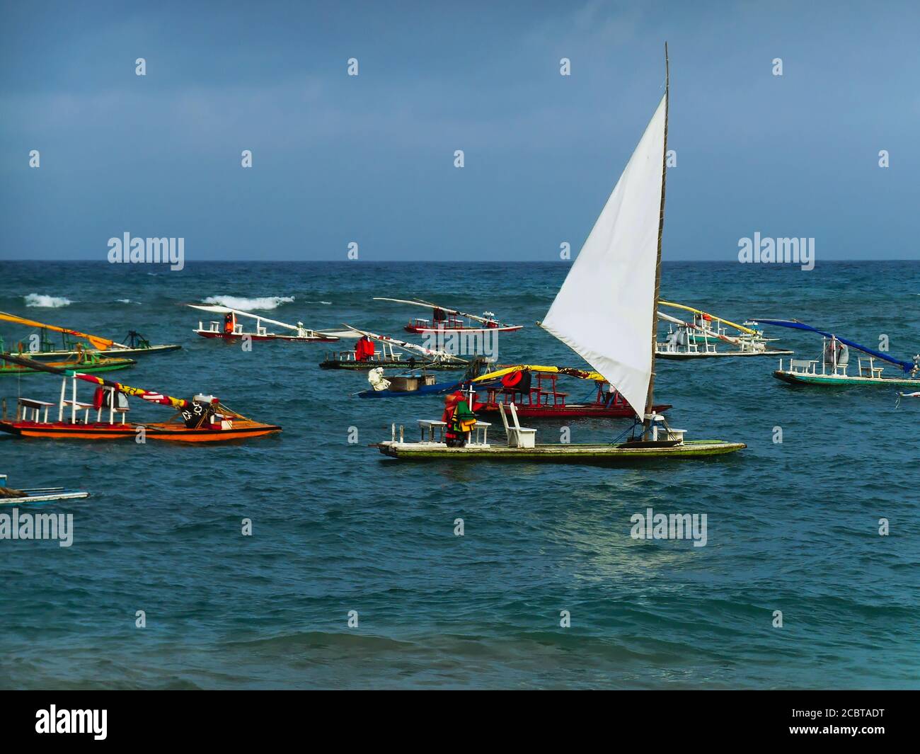 Una zattera di vele bianche che si ergono dalle altre ancorate in acque color smeraldo al largo della spiaggia di Porto de Galinhas. Foto Stock
