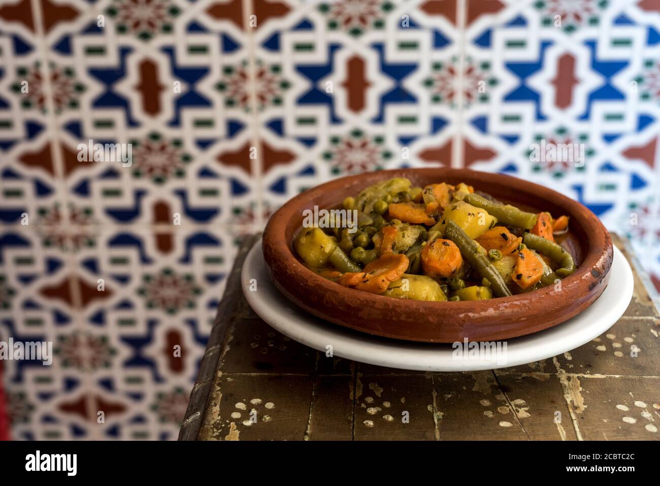 Tajine di verdure marocchine, con piselli di carota e patate dolci su  tavola di legno, con piastrelle arabiche tradizionali sullo sfondo Foto  stock - Alamy