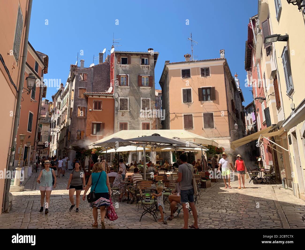 Turisti in una piccola piazza intorno a case colorate. Rovigno, Istria / Croazia. Foto Stock