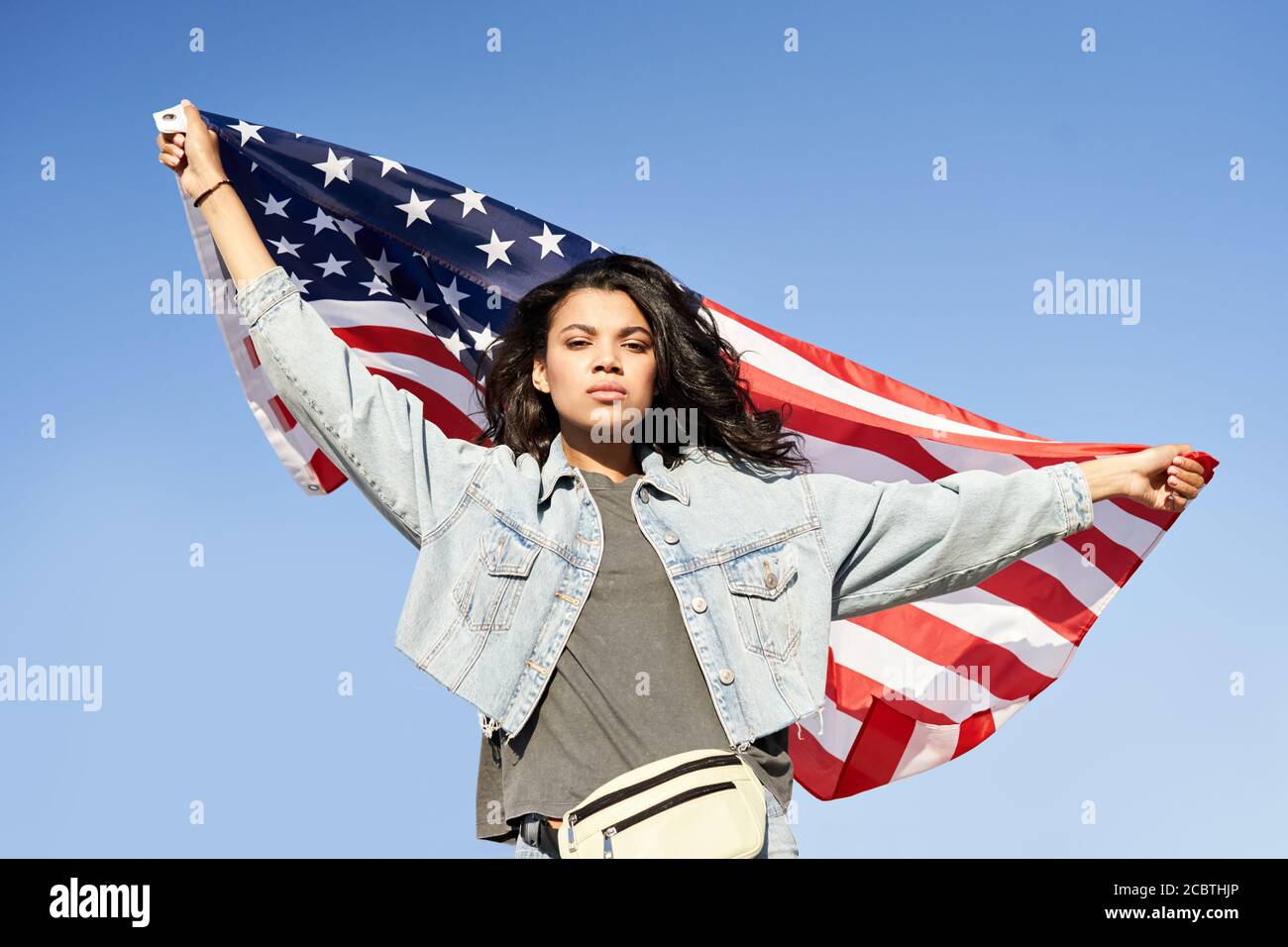 Orgogliosa donna afroamericana in piedi sulla strada che tiene la bandiera degli stati uniti. Foto Stock