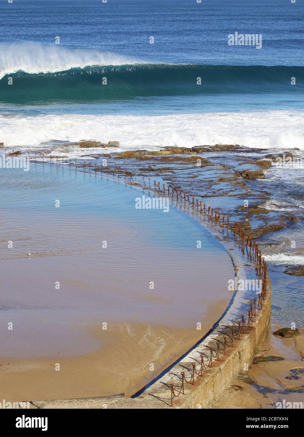 Una grande onda si spezza oltre le Terme oceaniche di Newcastle. Newcastle è la seconda città più grande del nuovo Galles del Sud e ospita molte eccellenti spiagge per il surf. Foto Stock