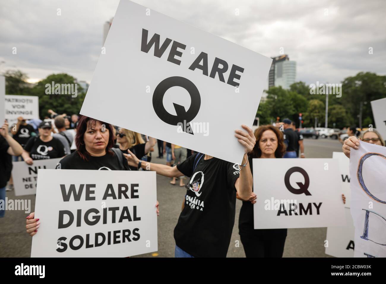 Bucarest, Romania - 10 agosto 2020: La gente visualizza i messaggi di Qanon sui cartelloni durante un raduno politico. Foto Stock