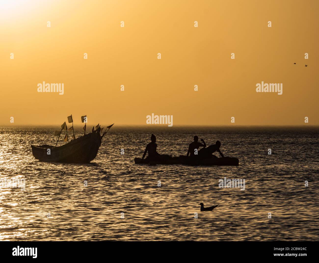 Tramonto sulla costa atlantica in Africa e le sagome di un peschereccio in acqua, Senegal, Africa Foto Stock