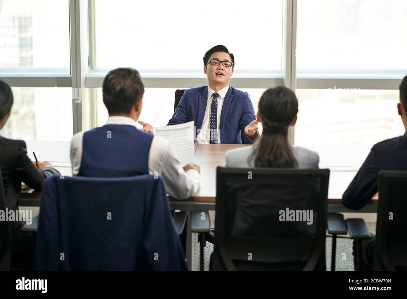 troppo fiducioso giovane uomo d'affari asiatico che parla grande di fronte di intervistatori di ore durante il colloquio di lavoro Foto Stock