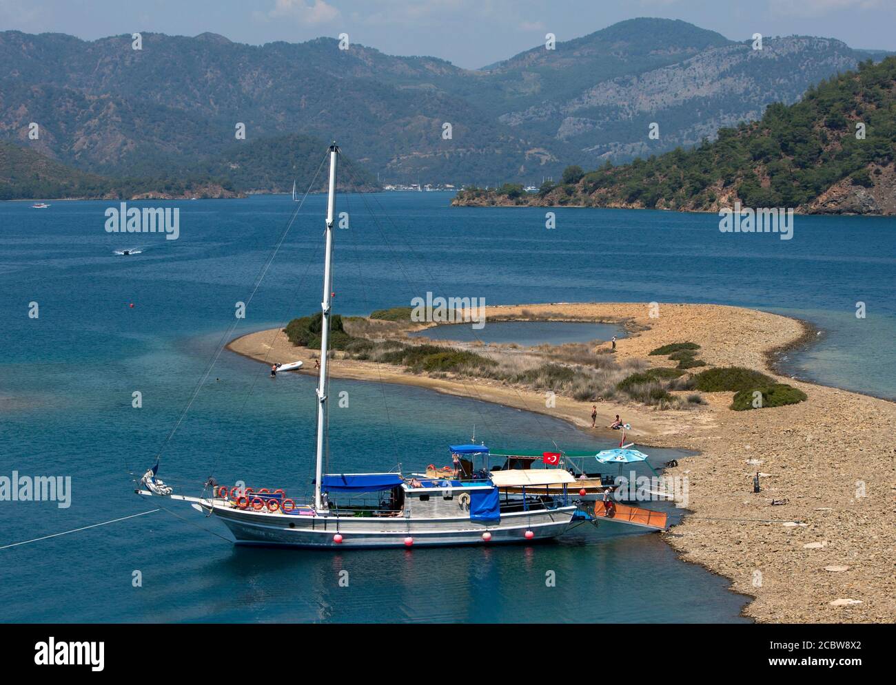 Una nave da crociera ancorata ad una piccola spiaggia nel Mediterraneo durante la crociera dell'Isola dei dodici di Fethiye al largo della Costa Turchese della Turchia. Foto Stock