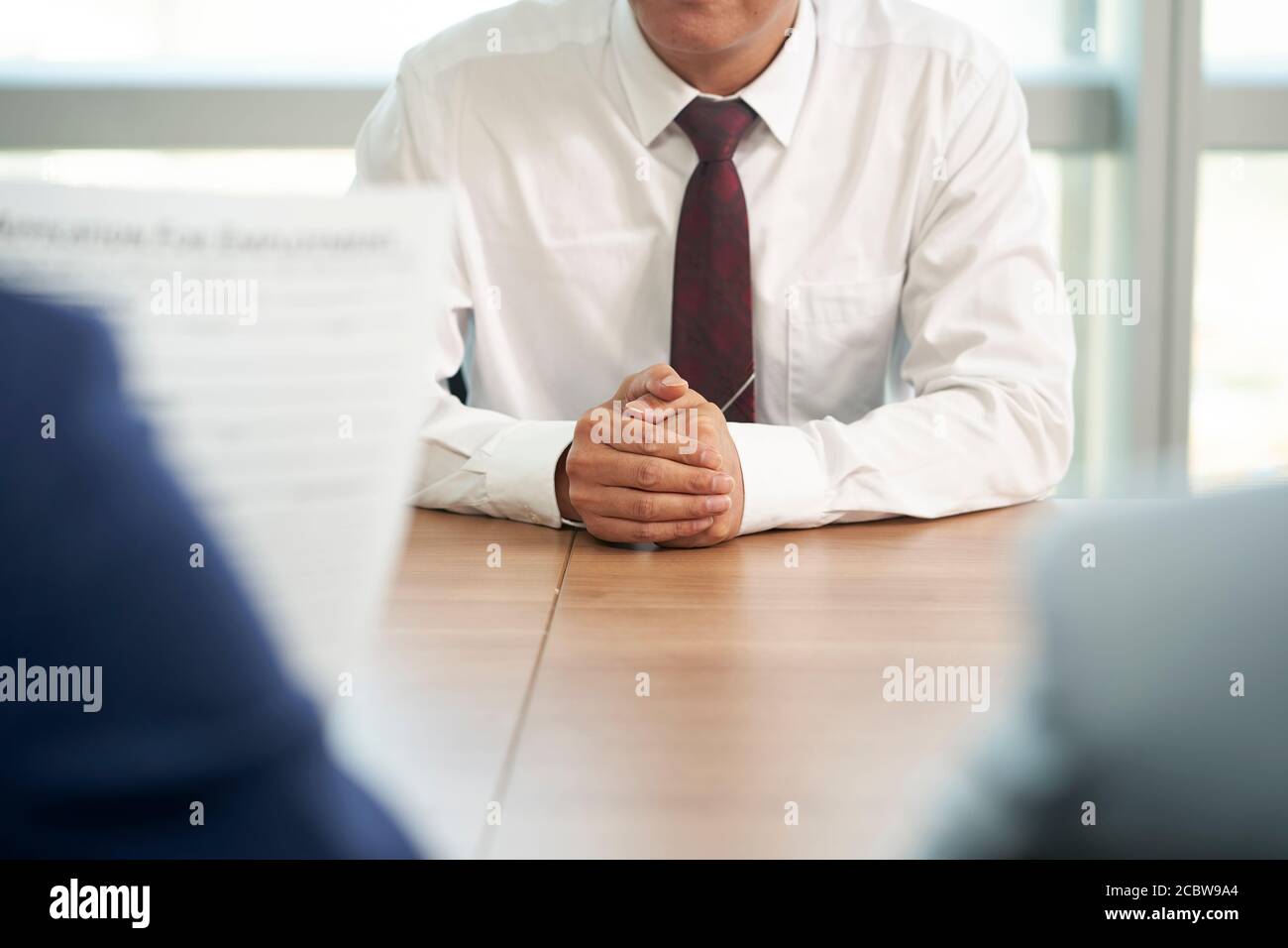 job seeker asiatico intervistato dal responsabile delle risorse umane in carica, concentrarsi sulle mani del candidato Foto Stock