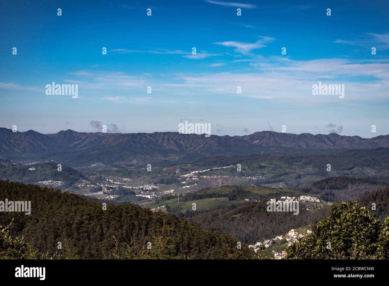 vista della città con la catena montuosa e il cielo blu luminoso dalla cima della collina al giorno immagine è presa dal picco di doddabetta ooty india. mostra la vista dall'alto Foto Stock