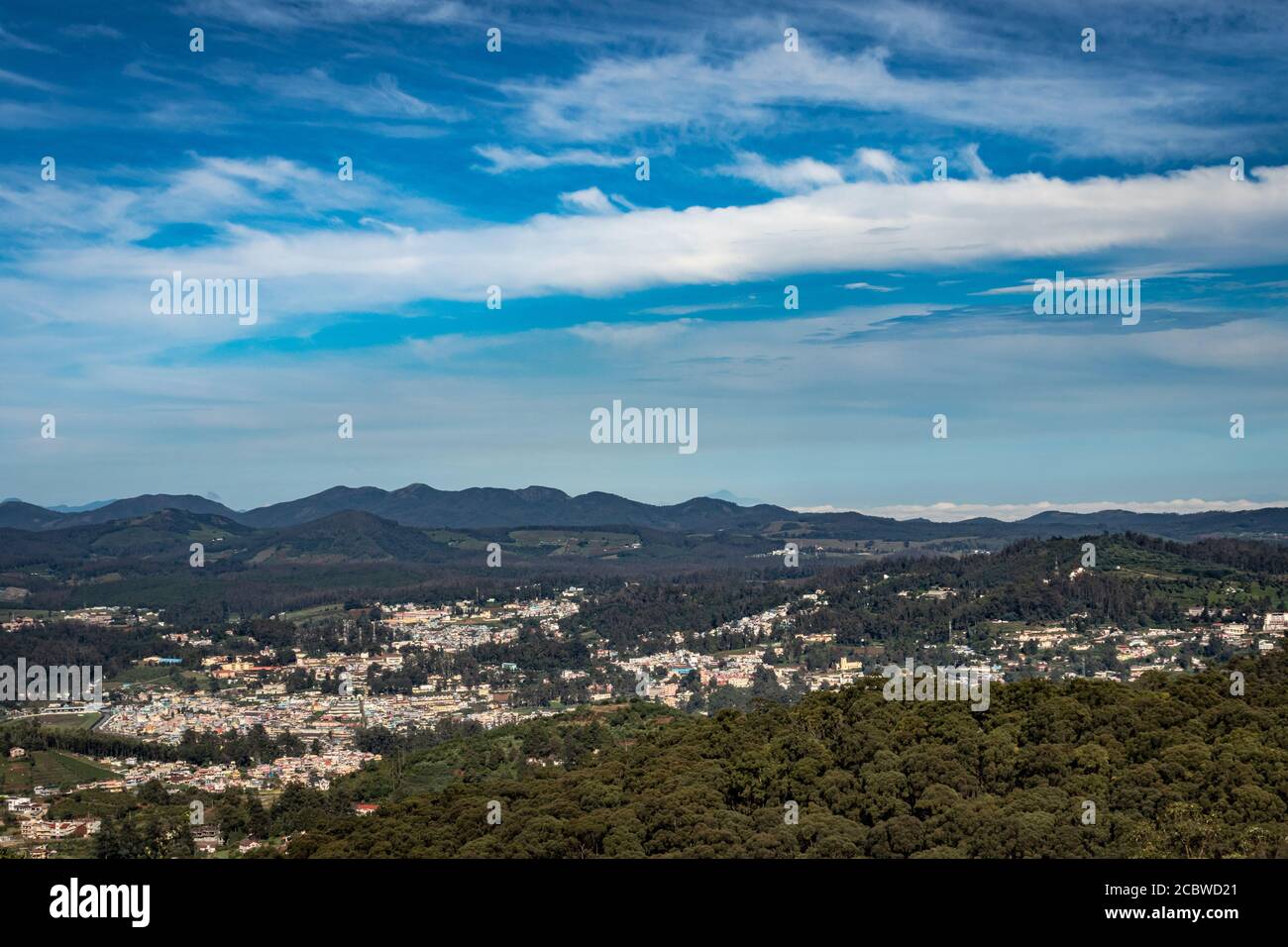 vista della città con la catena montuosa e il cielo blu luminoso dalla cima della collina al giorno immagine è presa dal picco di doddabetta ooty india. mostra la vista dall'alto Foto Stock