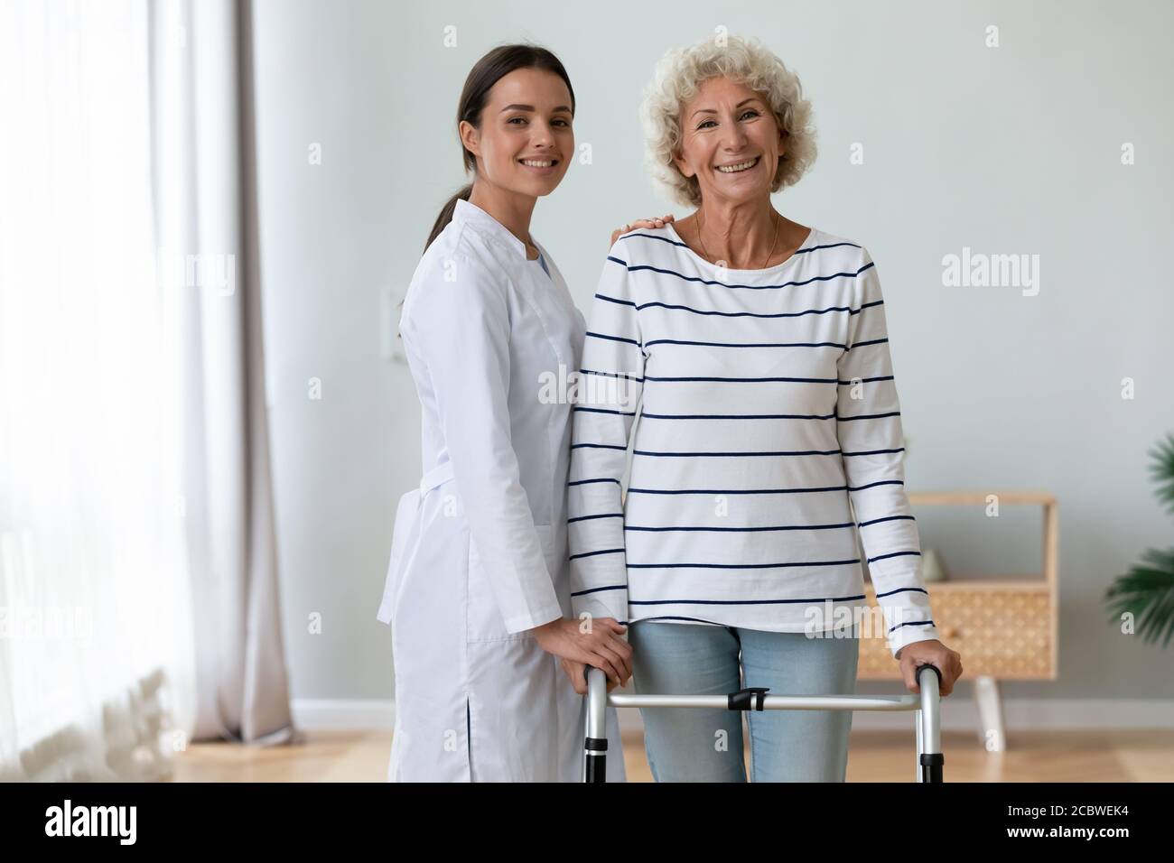 Ritratto di felice giovane lavoratore medico con paziente anziano disabile. Foto Stock