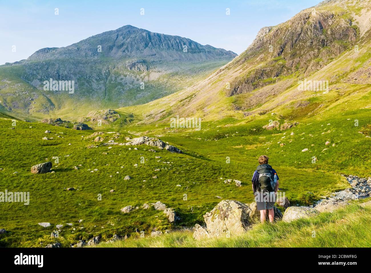 Ragazzo adolescente che cammina verso Bowfell, una montagna del Lake District, sopra l'alta valle di Esk Foto Stock