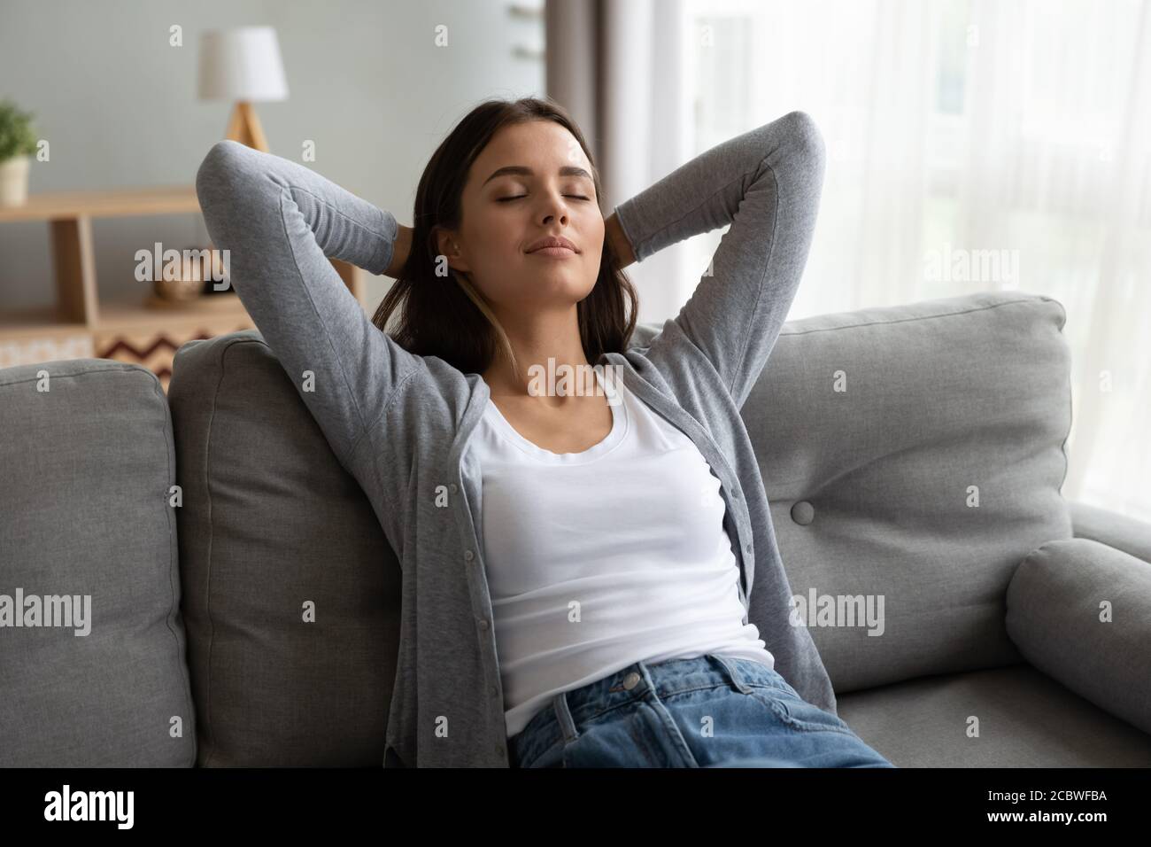 Giovane bella donna tranquilla che sogna sul divano. Foto Stock