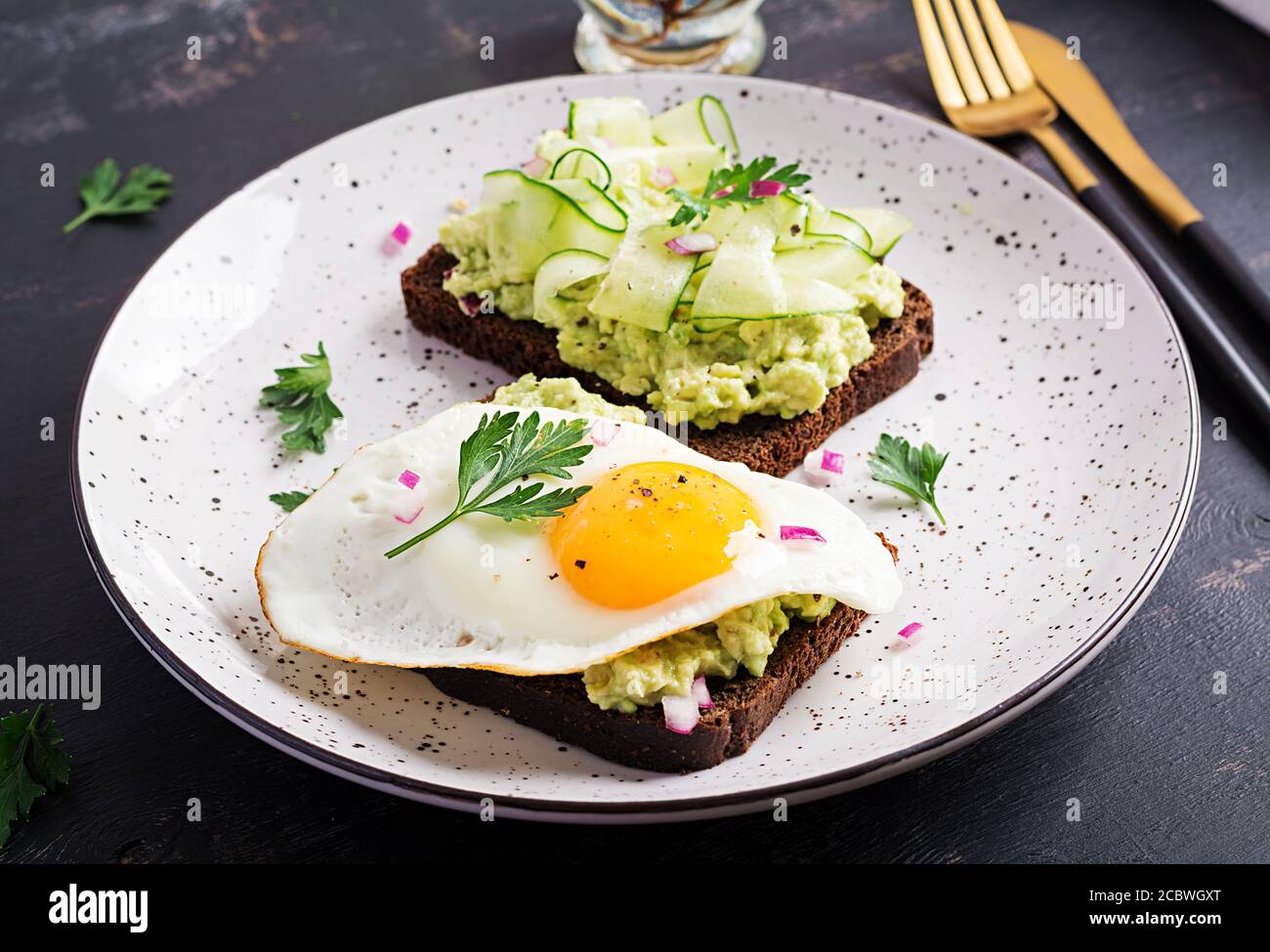 Colazione sana. Sandwich con avocado guacamole, cetriolo e uova fritte, per una sana colazione o uno spuntino. Foto Stock