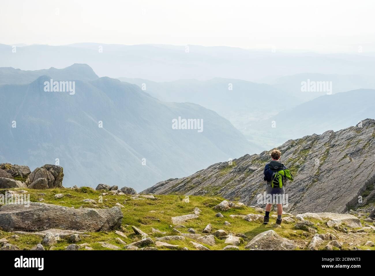 Ragazzo adolescente a Three Tarns a Bowfell, Lake District National Park. Langdale Pikes in lontananza Foto Stock