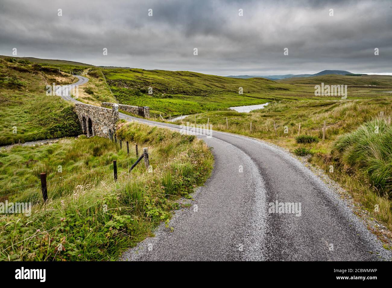 Una strada rurale che si torce attraverso le colline Di Connemara Foto Stock