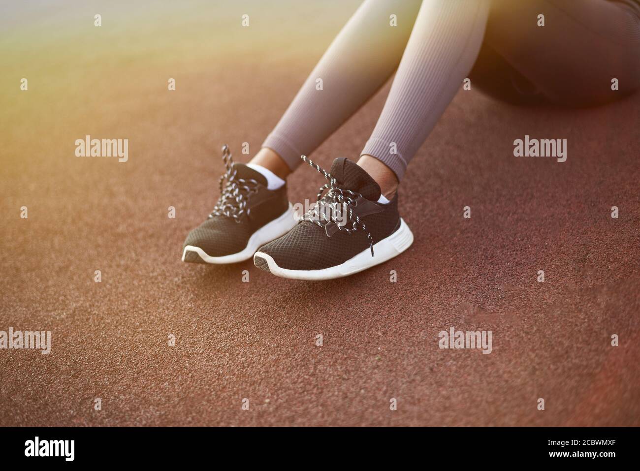 Gambe di una ragazza nera in leggings sportivi e sneakers su un terreno sportivo in strada. Foto Stock