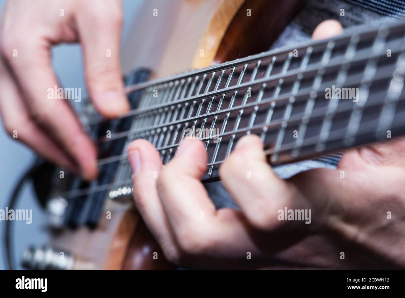 Primo piano della chitarra basso le mani del giocatore, soft il fuoco selettivo, live musica tema Foto Stock