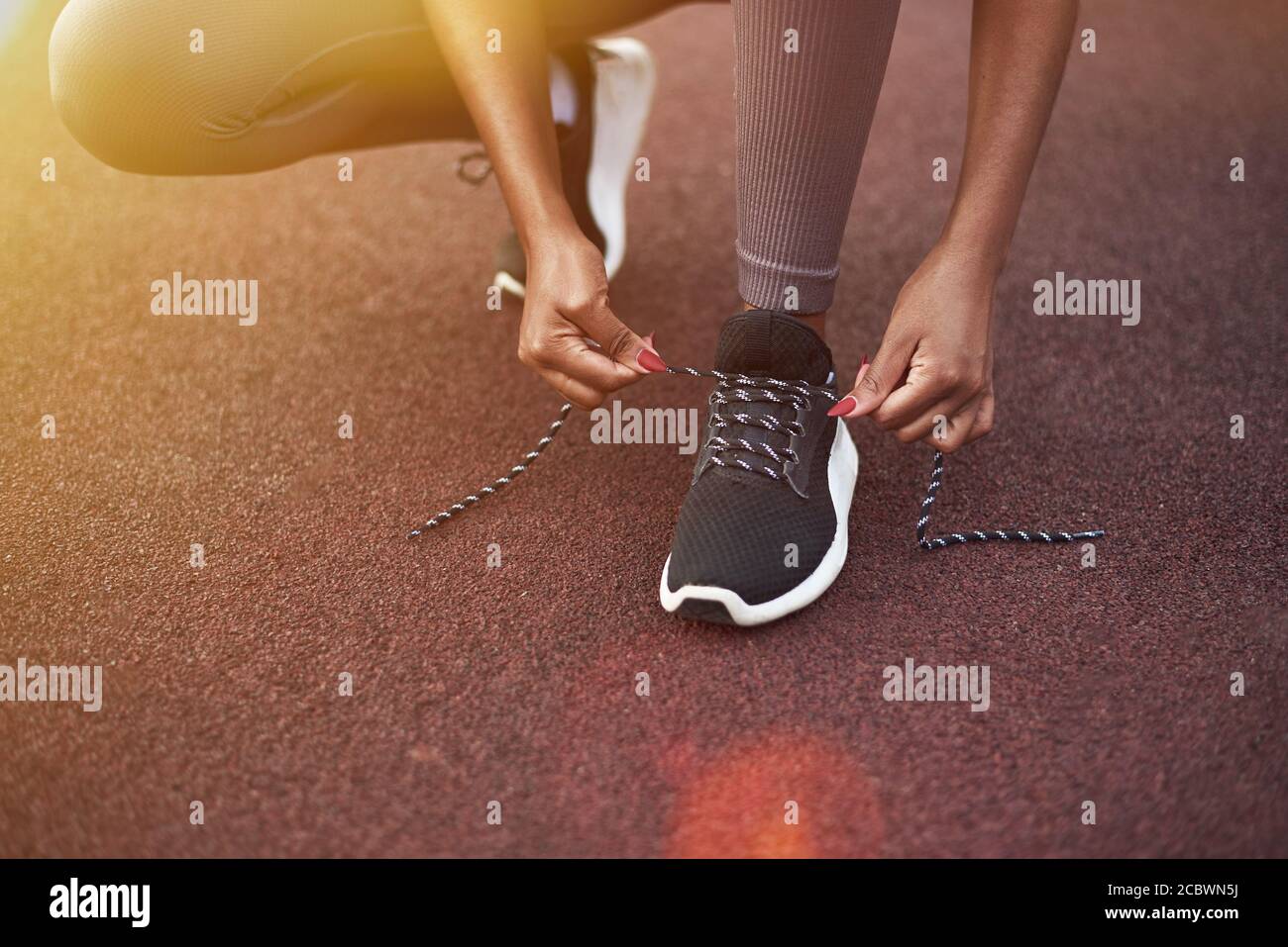 Black girl indossa le sue sneakers mentre fa sport per strada. Concetto di fitness all'aperto. Foto Stock
