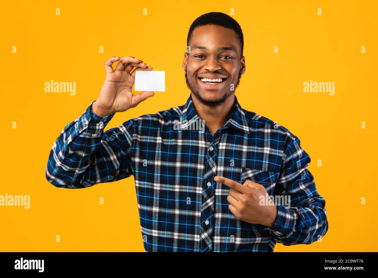 Black Guy Holding Blank Visiting Card in piedi su sfondo giallo Foto Stock