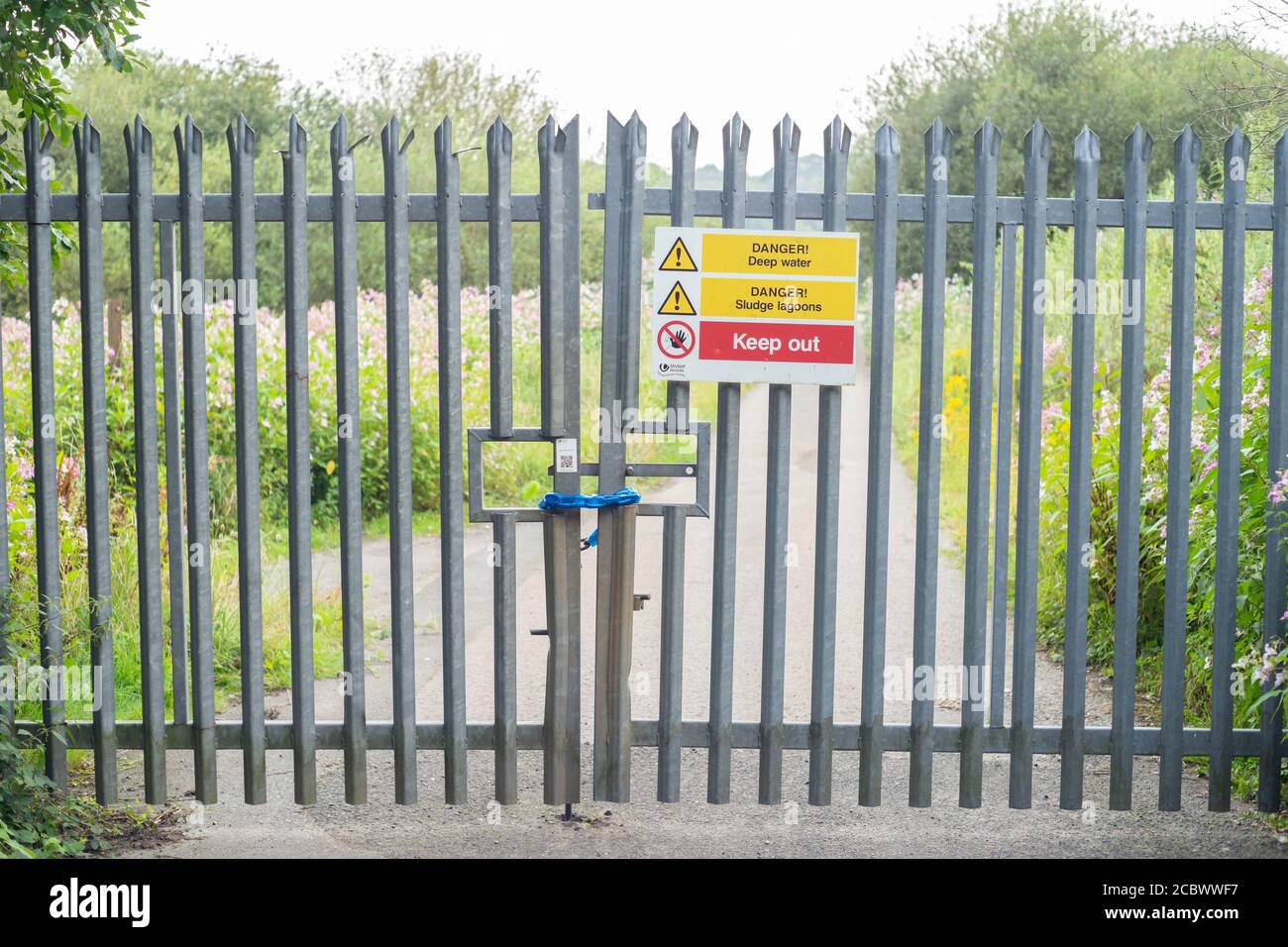 Cancello chiuso con vari avvertimenti di pericolo vicino a un impianto di trattamento delle acque della United Utilities su Red Rock Lane, Stoneclough, Inghilterra, Regno Unito Foto Stock