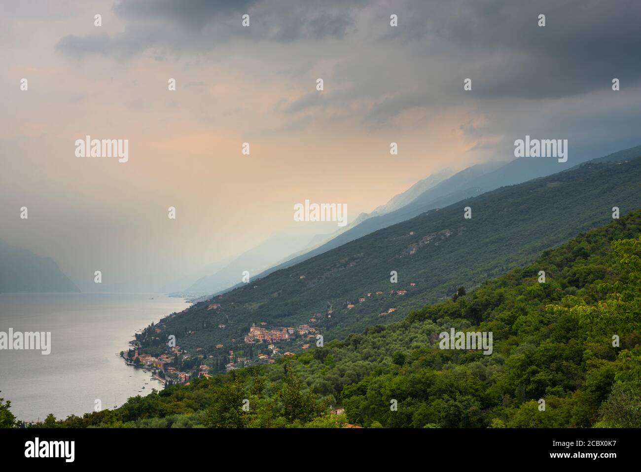 Oscure nubi di temporale sul Monte Baldo e villaggi sul lago di Garda settentrionale, Veneto, Trentino, Italia Foto Stock