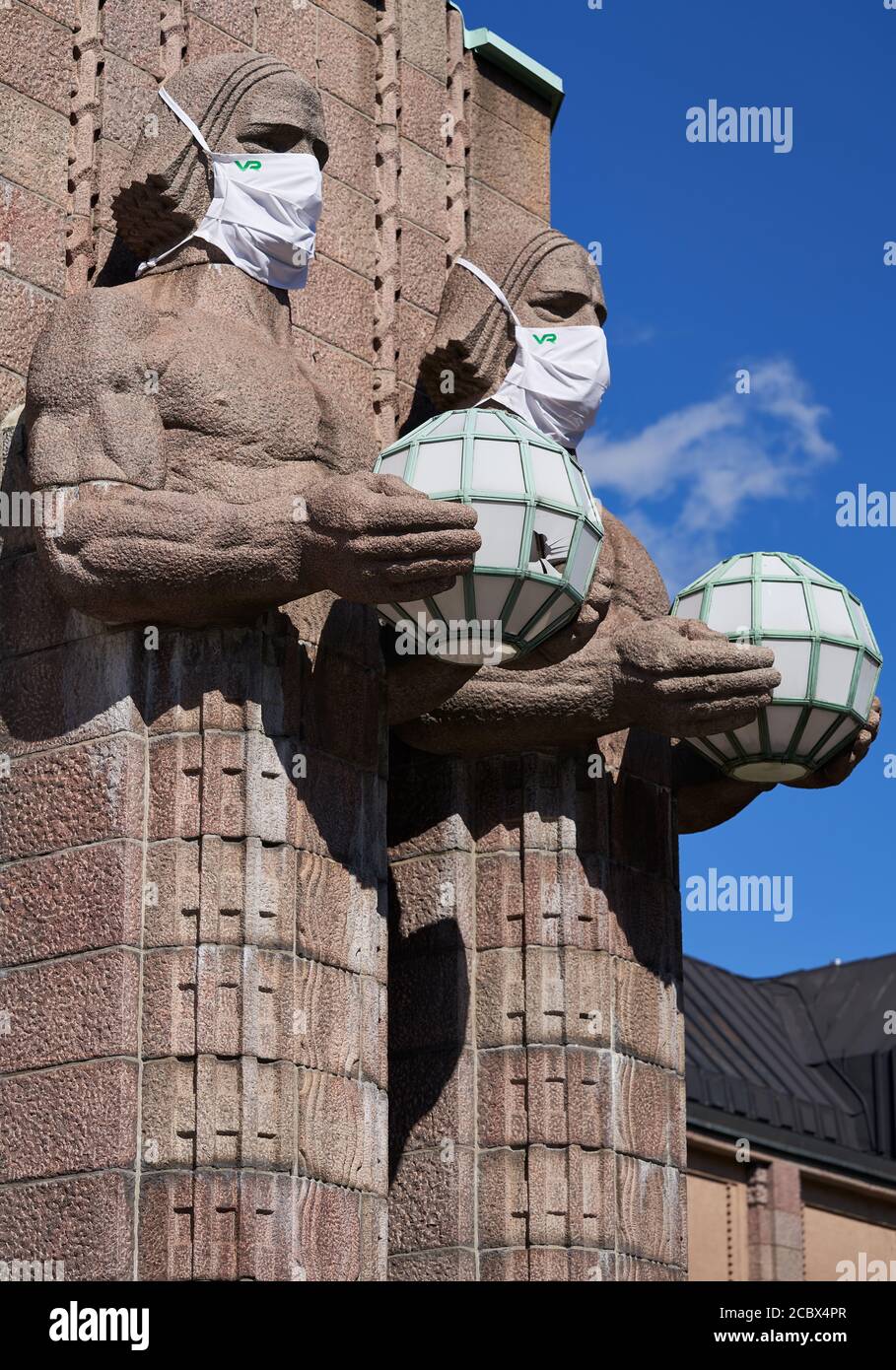 Helsinki, Finlandia - 16 agosto 2020: Iconiche statue di uomini in pietra sul lato dell'ingresso alla stazione ferroviaria centrale di Helsinki decorate come indossabili Foto Stock