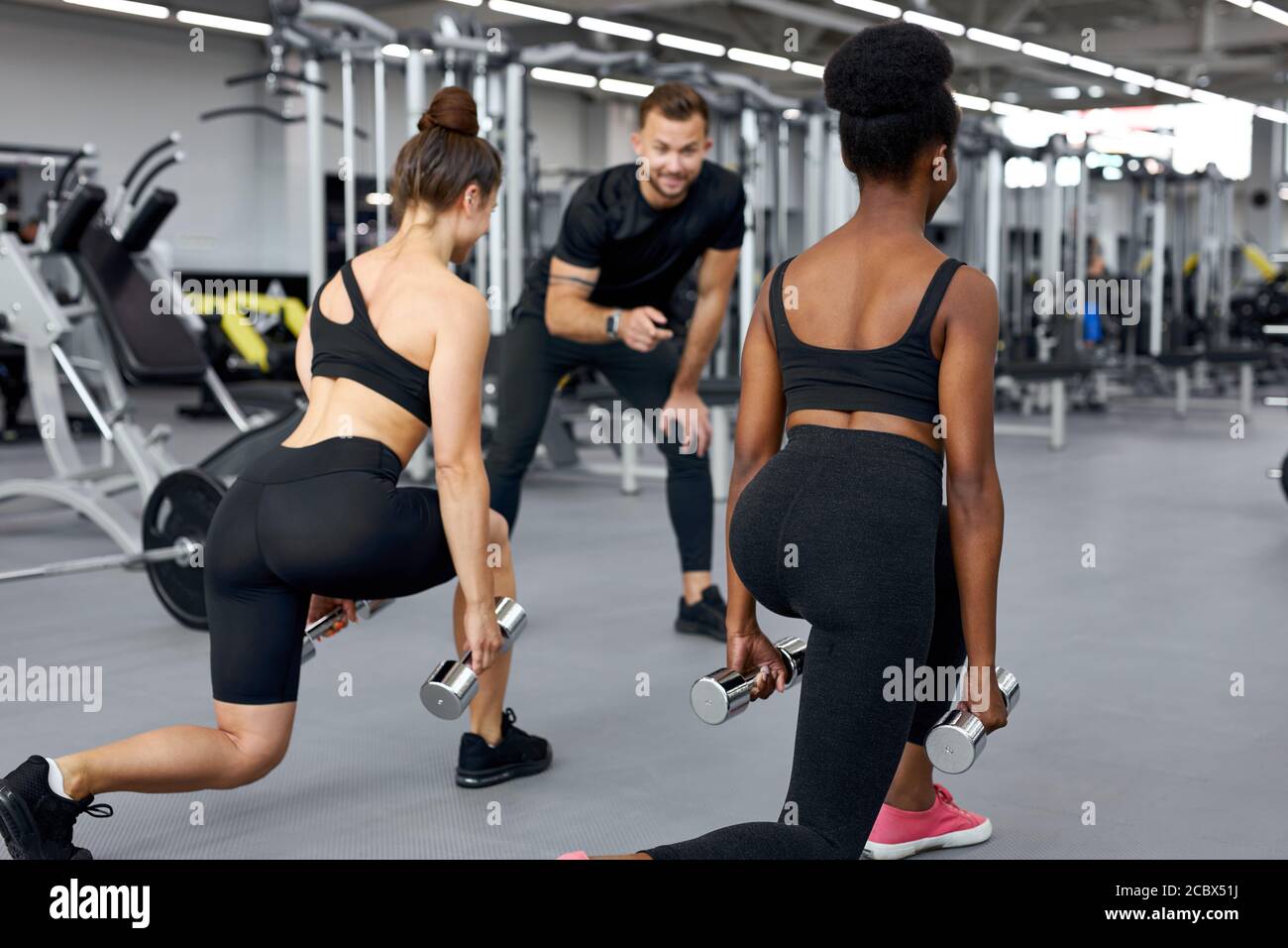 il formatore traccia la correttezza dell'esercizio in palestra, insegna alle persone a svolgere esercizi con pesi Foto Stock il formatore traccia la correttezza dell'esercizio in palestra, insegna alle persone a svolgere esercizi con pesi Foto Stock