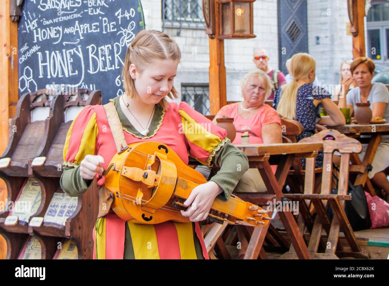 Sulla strada della città vecchia di Tallinn ragazza in un costume nazionale regola gli strumenti folk Foto Stock