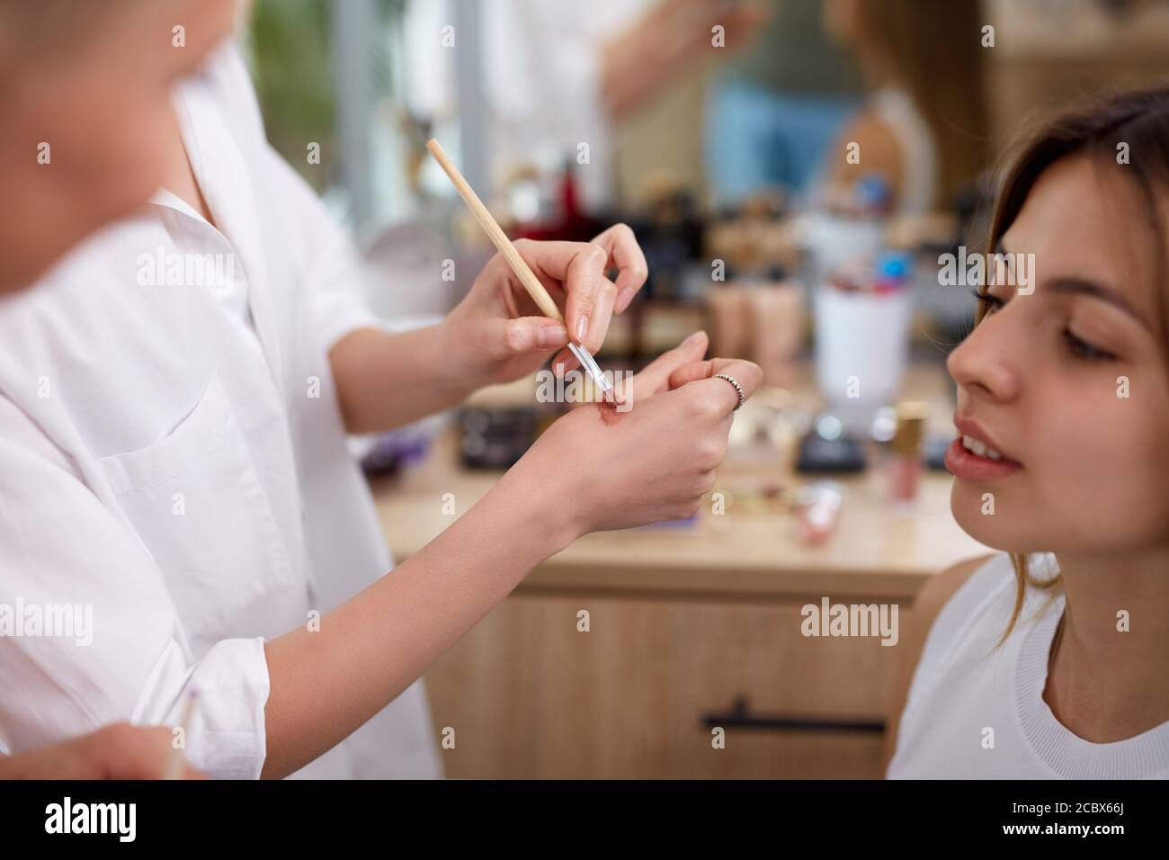 il professionista make-up artista o visagist applica i cosmetici a portata di mano prima di applicarli sul viso, in salone di bellezza Foto Stock