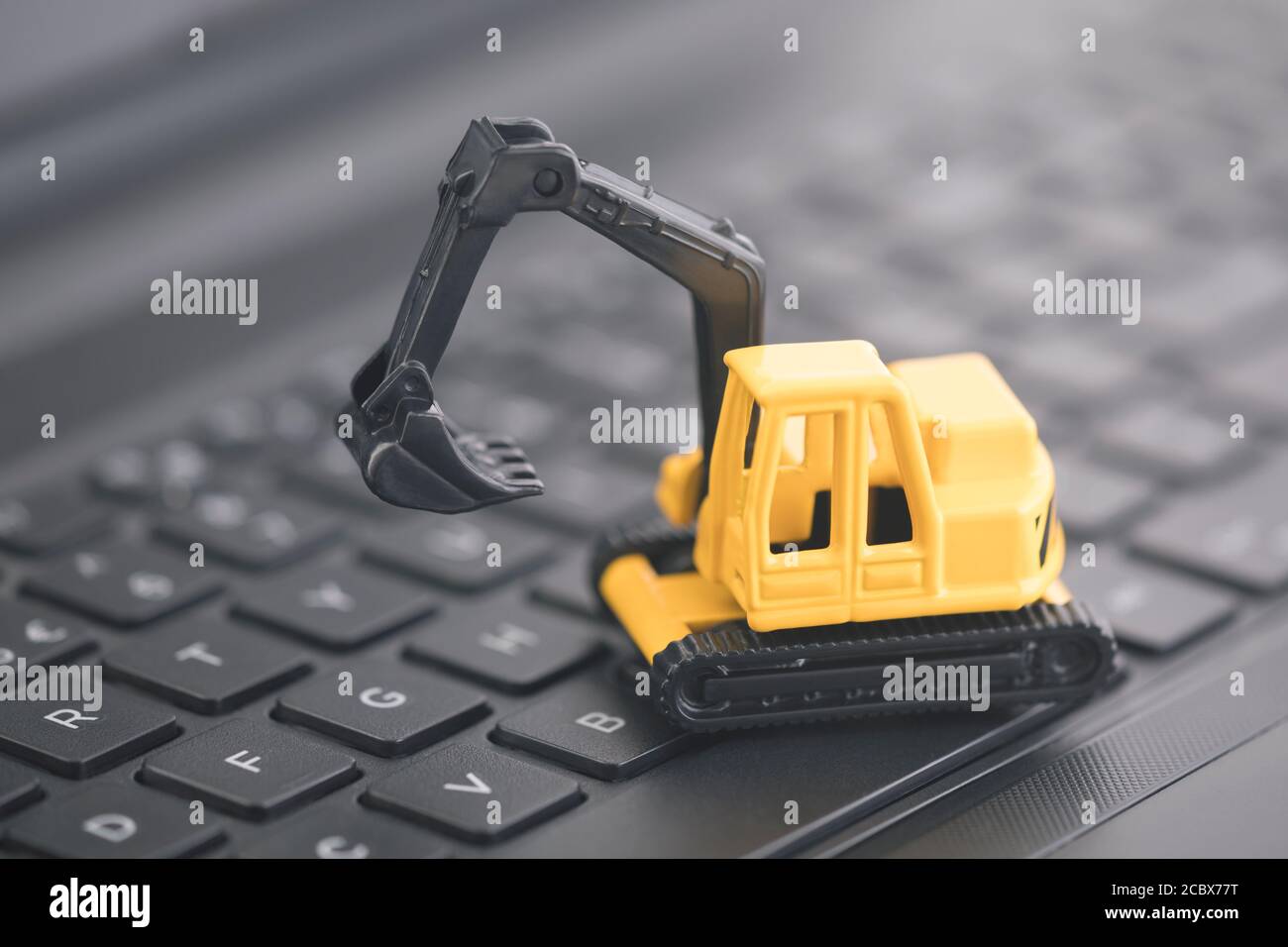 La miniatura dell'escavatore lavora su un portachiavi nero per laptop Foto Stock