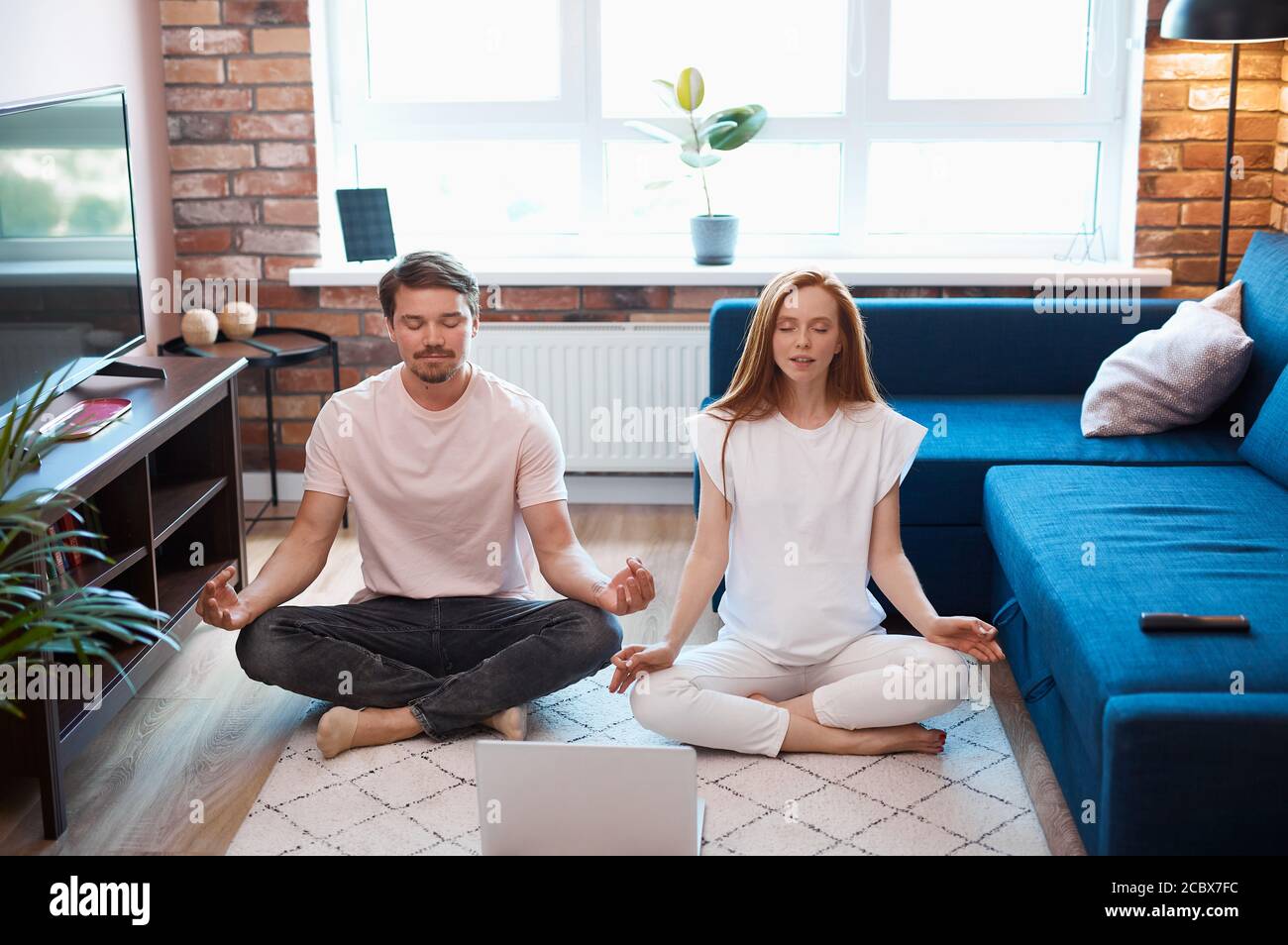 ragazza rossa e ragazzo bearded coinvolti nello yoga, giovane coppia sposata condurre uno stile di vita sano, pratica yoga, in posa di loto Foto Stock