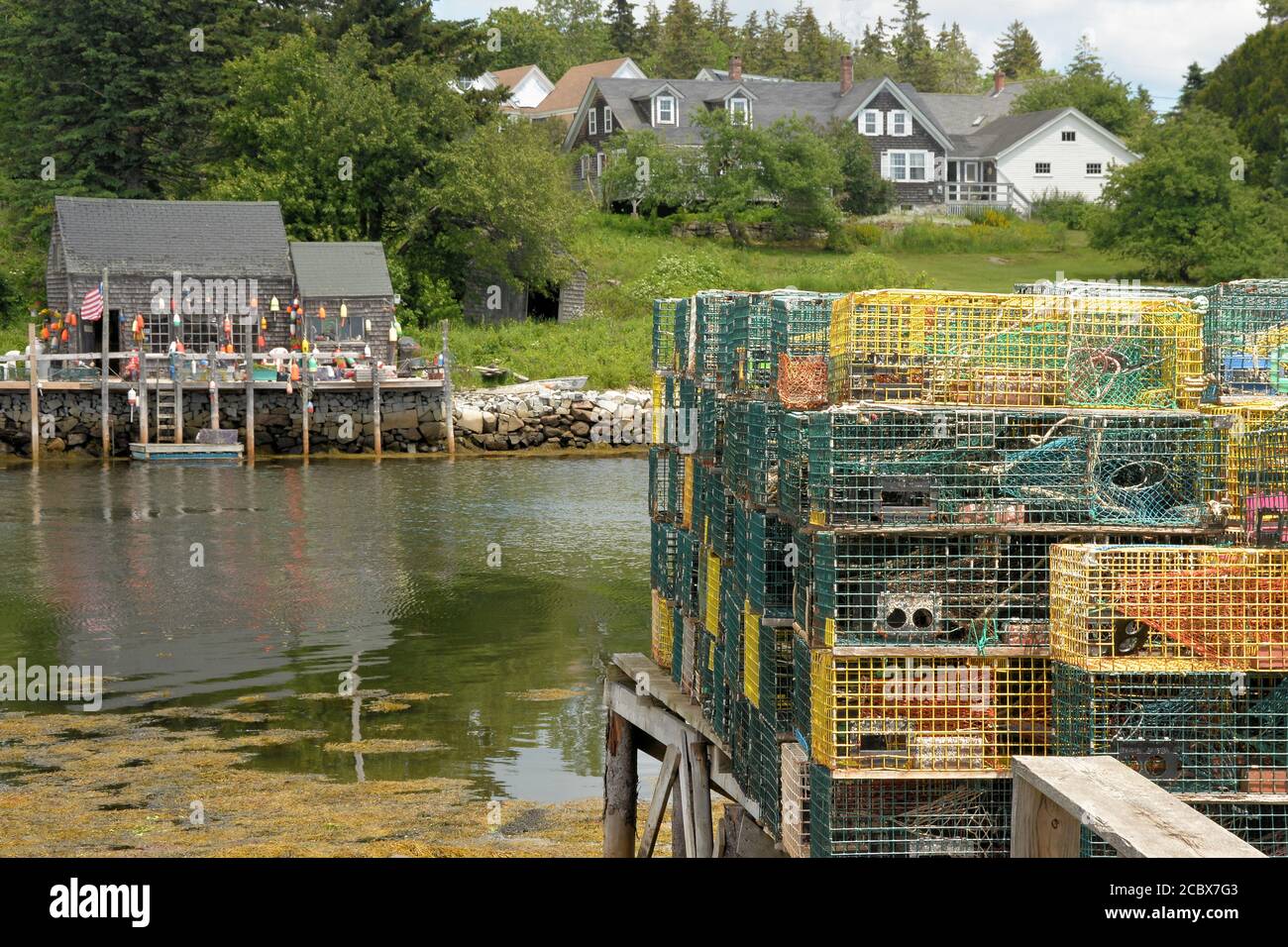 Pittoresco villaggio di pescatori di Port Clyde, Maine. Trappole di aragosta accatastate sul molo nel porto e zacca di aragosta decorata con boe colorate. Foto Stock