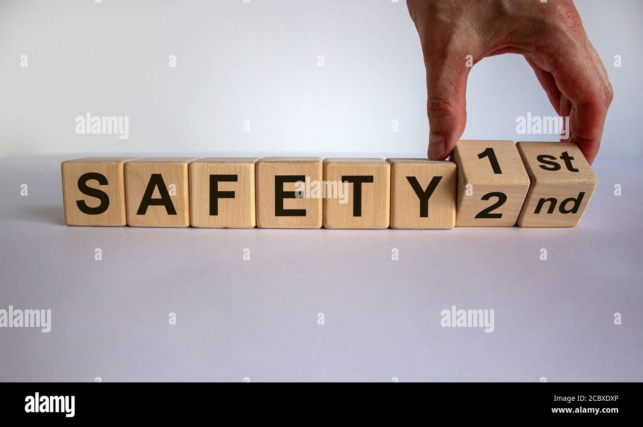 La mano trasforma un cubo e cambia l'espressione "sicurezza secondo" in "sicurezza prima". Splendido sfondo bianco, spazio per la copia. Concetto aziendale. Foto Stock